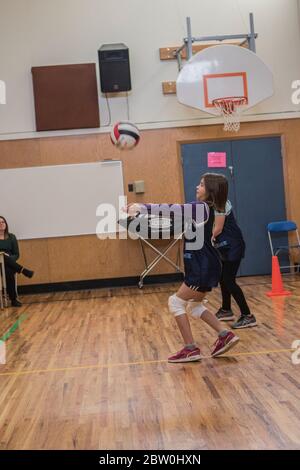 Filles volley-ball, 8 à 10 ans, acceptant servir et essayant de se mettre pour retourner le ballon. Banque D'Images