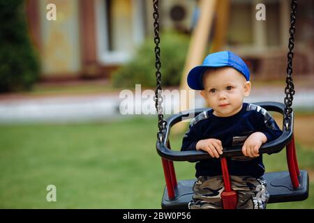 Beau garçon de 1-2 ans, assis sur une balançoire, un terrain de jeu, gros plan Banque D'Images