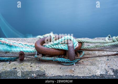 anneau d'amarrage sur le quai avec cordes et amarres serrées autour. Photo en exposition prolongée. L'eau en arrière-plan Banque D'Images