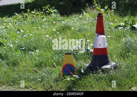 Deux cônes de trafic différents abandonnés sur un champ de unkempt surcultivé Banque D'Images