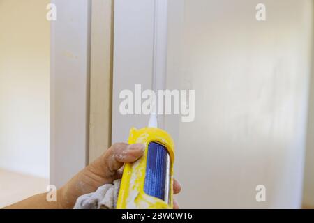 Appliquer du silicone sur la garniture de porte de moulage avec un pistolet à calfeutrer Banque D'Images