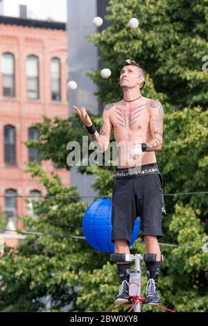 Saint John, Nouveau-Brunswick, Canada - le 13 juillet 2017 : Festival annuel des Buskers on the Bay. Un homme au sommet d'un poteau élevé jongle avec des boules blanches. Banque D'Images