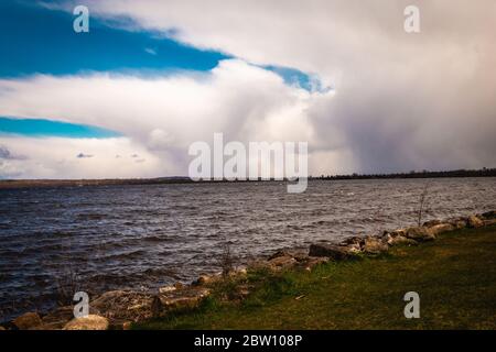 Des nuages blancs épais, avec des parties sombres montrant de la pluie au loin, empiétent sur un ciel bleu au-dessus d'une rivière Ottawa instable au Canada. Banque D'Images