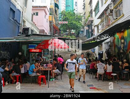 Les gens mangeant et buvant dans des restaurants et des bars extérieurs lors d'une journée ensoleillée dans les rues arrière. Hong Kong Banque D'Images