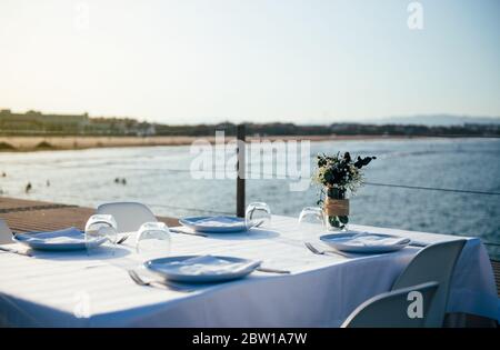 Table de restaurant avec nappe blanche sur la terrasse au bord de la mer concept de retour à la normale pendant la pandémie Banque D'Images