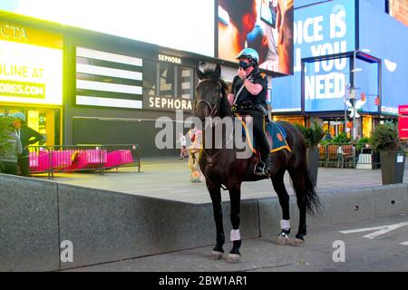 New York, New York, États-Unis. 27 mai 2020. Un officier de l'unité montée NYPD, visage protégé par un masque, surveille Times Square tout seul avec son partenaire à quatre pattes dans un quartier généralement bondé de touristes toujours friands de photos. Cette patrouille s'appelle les flics de 10 pieds de New York. Les officiers de ce groupe d'élite de 55 chevaux se font membres d'une force unique dans la ville. Crédit : Marie le BLE/ZUMA Wire/Alay Live News Banque D'Images