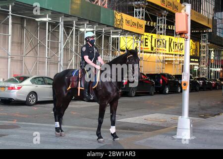 New York, New York, États-Unis. 27 mai 2020. Un officier de l'unité montée NYPD, visage protégé par un masque, surveille Times Square tout seul avec son partenaire à quatre pattes dans un quartier généralement bondé de touristes toujours friands de photos. Cette patrouille s'appelle les flics de 10 pieds de New York. Les officiers de ce groupe d'élite de 55 chevaux se font membres d'une force unique dans la ville. Crédit : Marie le BLE/ZUMA Wire/Alay Live News Banque D'Images