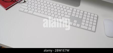 Plan court d'un simple bureau avec des ordinateurs, des lunettes, un carnet et un espace de copie sur une table blanche Banque D'Images