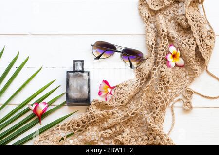 parfum, lunettes de soleil, crochet, feuille de noix de coco et fleurs frangipani des accessoires style de vie femme se détendre dans l'arrangement d'été plat de style de pose sur blanc Banque D'Images