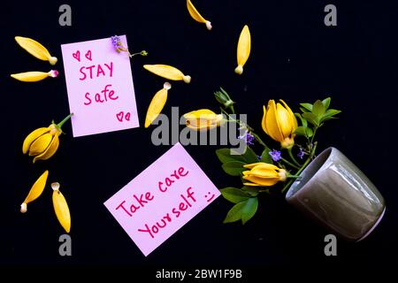 prenez soin de vous, séjour salf carte de message écriture avec des fleurs jaunes ylang ylang arrangement plat poser style carte postale sur fond noir Banque D'Images