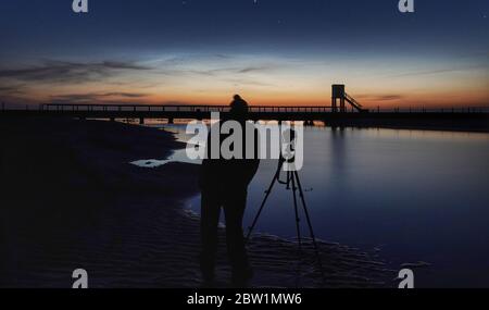 Un photographe fait la queue à la refuge Hut pendant le crépuscule astronomique sur la chaussée de l'île Sainte menant à l'île Sainte dans le Northumberland. Banque D'Images