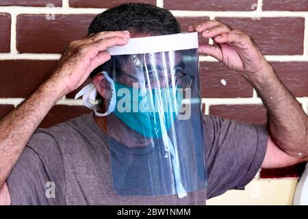 (200529) -- LA HAVANE, 29 mai 2020 (Xinhua) -- Ruben Ruiz, fils d'Iraida Hernandez, essaie un masque médical en matériaux recyclés chez lui, à la périphérie de la Havane, Cuba, le 27 mai 2020. Iraida Hernandez, 87 ans, ne s'attendait pas à retourner à sa vieille machine à coudre à son âge avancé, mais la nécessité de protéger sa famille la replace devant les rouleaux de fils et les coupures de tissu. La femme au foyer, qui vit à la périphérie de la Havane, fait des masques pour protéger ses proches et ses voisins de la COVID-19. Hernandez n'est pas seul. Son fils, Ruben Ruiz, technicien en construction civile, est également Banque D'Images