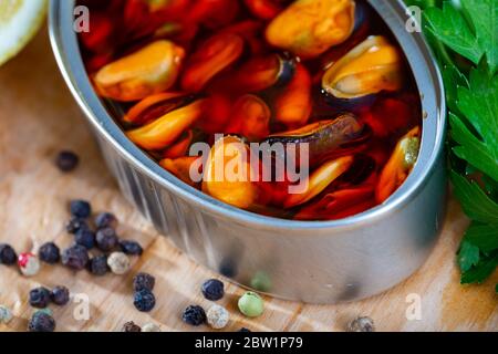 Peut ouvrir des moules marinées à l'huile épicée aux herbes et citron sur table en bois Banque D'Images