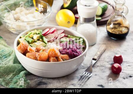 Bol à pique, salade de poisson hawaïenne traditionnelle avec riz, avocat, concombre et radis sur fond clair Banque D'Images