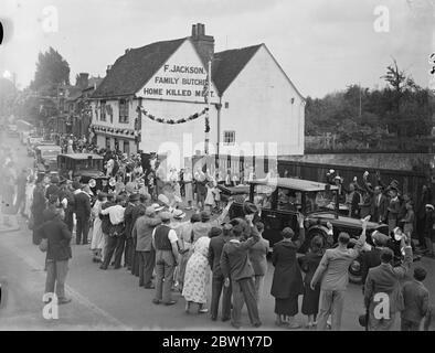 King et Queen font un détour de 3 kilomètres pour traverser un village en route vers Windsor. En réponse à une demande faite au Palais de Buckingham par les habitants de Colnbrook, un village sur la route de Bath le Roi et la Reine ont fait un détour de 2 miles sur leur route d'État de Londres à Windsor afin de passer par le village. La voiture royale a été ralentie à un rythme de marche et le capot a été abaissé de sorte que la foule puisse voir le roi et la reine et les princesses. Photos : la voiture royale a applaudi lorsqu'elle passait par le village de Colnbrooke. [La publicité murale se lit comme suit : F. Jackson Family Butchers, Home tué Meat Banque D'Images