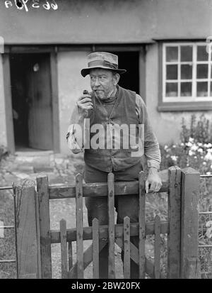 Depuis une petite auberge dans le village pittoresque de Bardfield, dans l'Essex, les anciens artisans et les personnages locaux typiques doivent diffuser aux Etats-Unis une impression de la vie de pays anglais comme elle l'a été pendant des siècles. Dans le taproom de l'Egle de propagation le wart-healer local, Uppy, deux professionnels thatchers et le professeur Harold Laski parlera dans le microphone et l'hôte de la mine, M. Harry Barnes, fermera le programme avec les derniers ordres et l'heure, monsieur, s'il vous plaît. Uppy (Charles Shephard Andrews) le guérisseur local photographié au-dessus de sa porte de jardin. Uppy peut guérir des verrues en quelques semaines sans même voir salut Banque D'Images