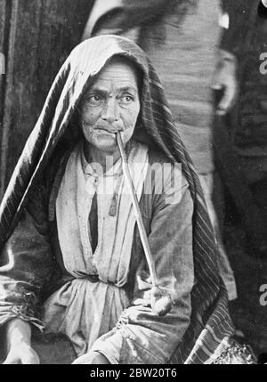 Femme juive âgée, pipe-addict d'un ghetto russe habillé de tissus épais et de châle. Elle fume avec satisfaction sa longue pipe, grossièrement faite de bois, dans le ghetto de Derbent / Derbend, Dagestan République sur les rives de la mer Caspienne URSS. 9 juillet 1937 Banque D'Images