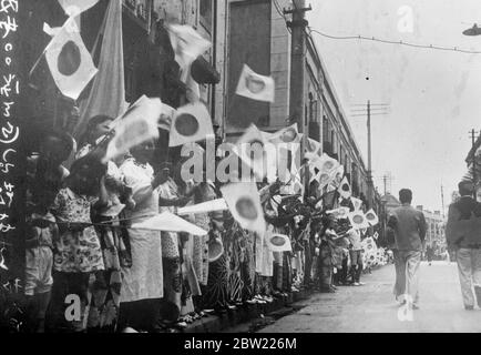 Des foules de femmes et d'enfants, dans leur village pittoresque de Kimonos, agitant le drapeau japonais portant le soleil levant symbolique alors qu'ils bordent les routes pour encourager les troupes quittant Tokyo pour renforcer les forces japonaises en Chine. Le Japon fait maintenant une grande pression sur Shanghai. 12 septembre 1937 Banque D'Images