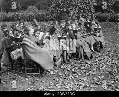 Il y a une pinceur dans l'air. Les enfants de l'école de St James's Park s'emparades dans des couvertures. L'automne a amené des vents de froid à Londres, et les élèves de l'école en plein air de St James's Park ont cherché refuge dans des couvertures pour se garder au chaud pendant les leçons. Expositions de photos, élèves en couvertures à l'école en plein air du parc St James's. 21 septembre 1937 Banque D'Images