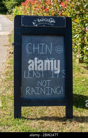 Panneau amusant devant le pub Onslow Arms disant que Chin Up au moins, il ne pleut pas ! Pendant la pandémie du coronavirus Covid-19, Loxwood, West Sussex, Royaume-Uni Banque D'Images