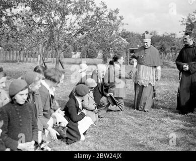 Embrasser l'anneau de l'Archevêque dans les jardins du houblon. L'archevêque de Southwark, le RT Rev P E Amigo, a fait sa visite annuelle dans les jardins du houblon de Kent aujourd'hui (dimanche) et a célébré une messe spéciale des cueilleurs de houblon à Horsmonden. Photos, une petite fille embrassant l'anneau de l'archevêque Mgr Horsmonden. 4 septembre 1938 Banque D'Images