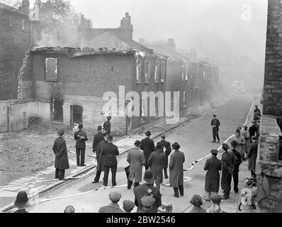 Des maisons royales ont brûlé à Willesden en présence du maire et de la brigade des pompiers. Les maisons d'arrivée, condamnées sous un plan de décharge de taudis a été délibérément mis en feu dans notre place Alpha Nord par la brigade de feu de Willesden. La paraffine et les copeaux de bois ont été utilisés pour démarrer le feu. Le maire de Willesden, Alderman, H R Prothero, et sa fille, Mlle Dilya Prothero (la Mayoress), étaient parmi ceux qui ont regardé le feu. Photos, les maisons bien ablaçantes. 4 mai 1938 Banque D'Images