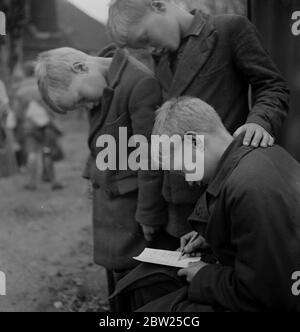 Les enfants de Cockney de la région de Sydenham Road de Croydon poussent dans les fermiers après leur évacuation dans la région de Woodingdean près de Brighton. Écrivant une maison à mère, les Twins Harold et John Margetts regardent leur frère Paul écrit sa lettre hebdomadaire. Banque D'Images