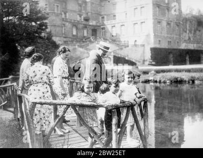 Président français avec ses petits-enfants en vacances château. Le parc Albert Lebrun de la République française, hôte du roi et de la reine lors de leur récente visite d'État en France, est en vacances au château de Vizille avec Mme Lebrun et des membres de leur famille. Photos, le président LeBrun, portant un cratère de paille, montrant à ses petits-enfants le lac dans le domaine du château de Vizille. Sur la photo figurent également Mme Jean Lebrun , la fille du Président en droit (au centre) et Mme Lebrun, épouse du Président (au premier plan, à l'arrière-plan). 3 août 1938 Banque D'Images