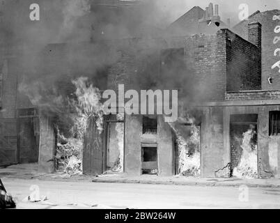 Des maisons royales ont brûlé à Willesden en présence du maire et de la brigade des pompiers. Les maisons d'arrivée, condamnées sous un plan de décharge de taudis a été délibérément mis en feu dans notre place Alpha Nord par la brigade de feu de Willesden. La paraffine et les copeaux de bois ont été utilisés pour démarrer le feu. Le maire de Willesden, Alderman, H R Prothero, et sa fille, Mlle Dilya Prothero (la Mayoress), étaient parmi ceux qui ont regardé le feu. 4 mai 1938 Banque D'Images