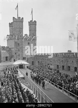 Debout sur l'endroit d'où, selon la légende, le premier prince de Galles a été montré aux chefs, le roi et la reine se sont présentés aux gens du pays de Galles au château historique de Caernarvon à la fin de leur visite de deux jours au pays de Galles. Le roi et la reine arrivant en procession à la tour de l'aigle du château. Derrière leur Majestés se trouve M. David Lloyd George, le gendarme du Château. 15 juillet 1937. Banque D'Images