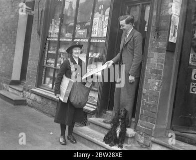 Une femme marchant bureau de poste dans Kent. Mlle Grace Coles, de Wrotham, Kent, est une postaliste auxiliaire et un bureau de poste itinérant. Elle a parcouru des kilomètres chaque jour pour livrer des lettres aux personnes vivant dans des régions éloignées de North Kent Downs, et vend également des timbres et des commandes postales sur elle et clique sur des lettres et des colis de maisons. Son tour commence sur le chemin du pèlerin et se termine à Labor à vain Hill. Elle marche plus de 2500 miles par an. Photos, Mlle Grace Coles livrant un colis à un villageois de Wrotham, Kent. 7 décembre 1937 Banque D'Images