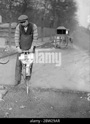 Un exercice sur route pratiquement silencieux. Moteur et semoir combinés. Un type révolutionnaire de forage routier compact, pratiquement silencieux, est utilisé dans un projet de reconstruction routière sur la colline de Muswell, Londres. Le semoir est entraîné par un petit moteur de moto à deux temps monté sur le châssis. Cette conception élimine le compresseur de jointure habituel et a besoin de compagnies aériennes enchevêtrées familières avec le semoir pneumatique. De plus, il est beaucoup plus facile à manipuler pour l'opérateur car les vibrations sont négligeables. Il est bon marché de fonctionner, ne coûtant que 15 shillings par jour pour l'essence et le pétrole. 3 décembre 1937 Banque D'Images