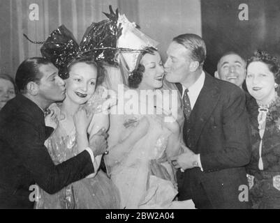 Un baiser Chevalier pour une Catherinette!. Maurice Chevalier, le film et acteur de scène (à droite) et Harry Pilcer, ancien danseur américain et associé de feu Gaby Deslys, volent des baisers de deux jolies Catherinettes à Paris lors des célébrations de la Saint Catherine. Les 'midinettes' de Paris de chaque maison de couture de la ville, qui avait atteint l'âge de 25 ans et qui étaient encore célibataires, ont célébré le Festival de Sainte Catherine, le Saint patron, en donnant le chapeau traditionnel et en faisant du joyeux jusqu'aux petites heures du matin. 26novembre 1937 Banque D'Images