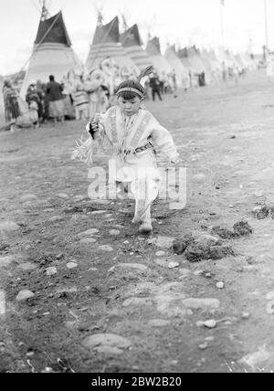 Légende originale : un minuscule papoose des Indiens rouges accueille le roi et la reine lorsque leurs Majestés ont été accueillis lors d'un grand rassemblement indien en l'honneur du roi et de la reine lors de leur visite royale au Canada. Le Roi et la Reine ont visité un campement des Indiens rouges à Calgary, en Alberta, au cœur de l'Ouest canadien, au pied des Rocheuses. 5 juin 1939 Banque D'Images