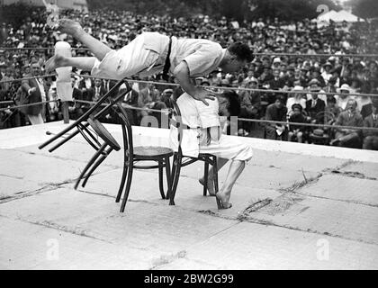 Démonstration de JU-Jitsu par M. George Pape, instructeur de gym à l'Eton College. M. Pape fait un saut en vol au-dessus d'une chaise pour démontrer une attaque. 14 juillet 1923 un art de l'auto-défense sans armes développé au Japon qui utilise des jets, des détends, des coups et tire la puissance supplémentaire de l'attaquant de son propre poids et de sa force. Banque D'Images