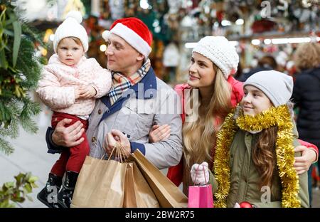 Famille heureuse avec deux beaux enfants filles tenant un sac en papier avec les achats au marché de Noël Banque D'Images