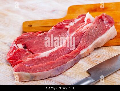 Entrecote de bœuf cru sur bois de bois avec romarin Banque D'Images