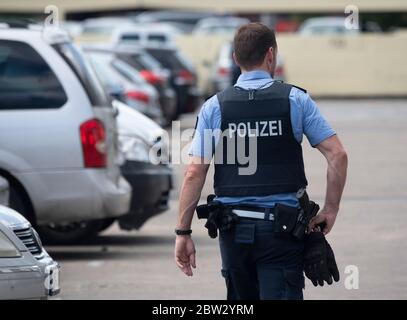 Dietzenbach, Allemagne. 29 mai 2020. Un policier traverse le parking d'une tour où la police et les pompiers ont été lancés de pierres et attaqués hier soir. Apparemment, les auteurs avaient intentionnellement mis deux feux pour attirer les officiers. Crédit : Boris Roessler/dpa/Alay Live News Banque D'Images