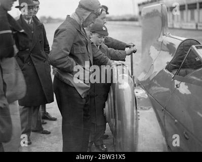 Sir Malcolm Campbell endommage les pneus sur la surface en béton de la voie de Brooklands . Les pneus ont été arrachés des roues de la célèbre voiture Bluebird sur sa première et seule apparition sur la piste Brooklands à la réunion d'ouverture du lundi de Pâques , lorsque Sir Malcolm a accéléré la célèbre voiture sur la piste de béton . Sir Malcolm Campbell examinant un des pneus détruits du Bluebird après la course . 28 mars 1932 Banque D'Images