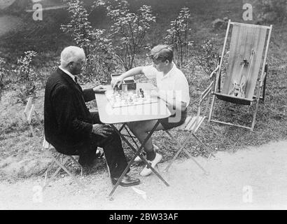 Célèbre violoniste de garçon , Yehudi Menuhin , en vacances . Yehudi Menuhin , violoniste de 15 ans qui a déjà gagné la renommée mondiale , passe des vacances près de Paris avant de venir à Londres pour une saison . Il fera une tournée en Amérique plus tard dans l'année . Yehudi Menuhin jouant aux échecs avec un vieil ami dans le jardin de sa maison de vacances près de Paris . 22 septembre 1932 Banque D'Images