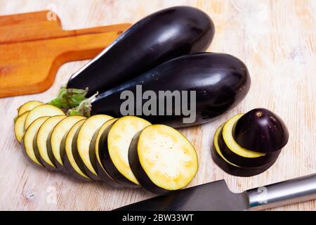 Aubergines entières et coupées en tranches sur une table en bois. Concept de nutrition saine Banque D'Images