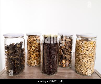 Stockage des aliments en vrac dans des pots en verre : champignons sauvages secs, muesli, chocolat et noix. Concept zéro déchet. Banque D'Images