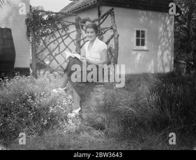 Peggy Scriven nouvel espoir de tennis anglais chez soi . Madame Peggy Scriven , la nouvelle espérance de tennis anglaise , qui a remporté cette semaine le Championnat de tennis français , battant Madame Mathieu , la championne française . Elle a passé sa première journée à la maison après sa visite en France, se reposant dans le jardin de sa maison à Byfleet Surrey . Photos ; Mlle Peggy Scriven se reposant dans le jardin de sa maison à Byfleet . Surrey . 7 juin 1933 Banque D'Images