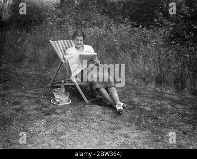 Peggy Scriven nouvel espoir de tennis anglais chez soi . Madame Peggy Scriven , la nouvelle espérance de tennis anglaise , qui a remporté cette semaine le Championnat de tennis français , battant Madame Mathieu , la championne française . Elle a passé sa première journée à la maison après sa visite en France, se reposant dans le jardin de sa maison à Byfleet Surrey . Photos ; Mlle Peggy Scriven se reposant dans le jardin de sa maison à Byfleet . Surrey . 7 juin 1933 Banque D'Images