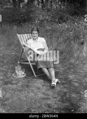 Peggy Scriven nouvel espoir de tennis anglais chez soi . Madame Peggy Scriven , la nouvelle espérance de tennis anglaise , qui a remporté cette semaine le Championnat de tennis français , battant Madame Mathieu , la championne française . Elle a passé sa première journée à la maison après sa visite en France, se reposant dans le jardin de sa maison à Byfleet Surrey . Photos ; Mlle Peggy Scriven se reposant dans le jardin de sa maison à Byfleet . Surrey . 7 juin 1933 Banque D'Images