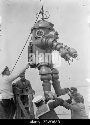 Nouvelle robe de plongée subit des tests en haute mer . Une robe de plongée inventée par M. J S Peress de Byfleet , Surrey , a subi des tests de performance en eau profonde en mer au large de Portsmouth . Il a été pris dans HMS Tedworth . La robe est un cylindre en acier avec un sommet en forme de dôme , qui est la tête , à laquelle sont attachés des pieds et des bras flexibles . Les bras sont fournis avec des pinces - comme des griffes comme des mains. La robe permet de plonger à des profondeurs beaucoup plus grandes que celles qui sont actuellement possibles . Un plongeur portant le nouvel appareil entrant dans l'eau du HMS Tedworth pour l'essai . 17 juin 1933 Banque D'Images