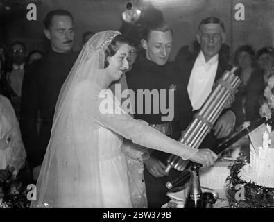 Une garde d'honneur des chemises noires a assisté au mariage de M. Ian Hope Dundas , chef d'état-major de l'Union britannique des fascistes et de Mlle Pamela Ernestin Dorman , qui est aussi fasciste à l'église Saint-Michel , Chester Square , Londres . Sir Oswald Mosley , dirigeant de l'Union britannique des fascistes , était le meilleur homme de la cérémonie . M. Dundas est le fils du regretté amiral Sir Charles Dundas de la Maison Inchgarbie , South Queensferry , Écosse . La mariée est une nièce du regretté Sir Ernest Shackleton , l' explorateur de l'Antarctique . Photos ; la mariée coupant le gâteau avec une hache surveillée par Sir Oswald Banque D'Images