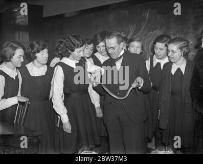 Les écolières achètent un python vivant comme animal de compagnie . Les filles de l'école de comté de Trinity , , Wood Green , londres ont été présentées avec un python comme animal de compagnie , le reptile est de trois pieds de long mais la probaly va croître à six ou sept pieds en quelques années . Il leur a été présenté par Lieut Col R H Elliot , le distingué spécialiste des yeux , les filles ont souscrit une partie du coût entre elles et les garçons ont construit une cage en bois pour le serpent . La photo montre Mme Emrys Jones , épouse du directeur de Trinity County School , Woodgreen , un amant de serpents montrant aux filles comment le tenir . 24 janvier 1934 Banque D'Images