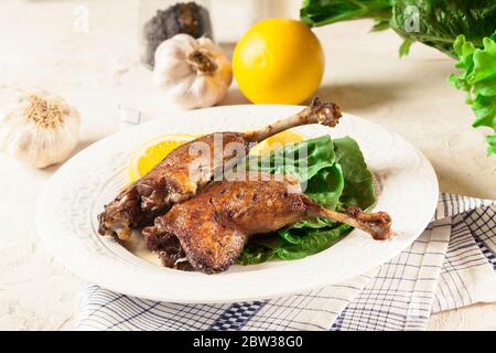 Les pattes de canard confite avec de l'orange et de la salade sur une assiette blanche Banque D'Images