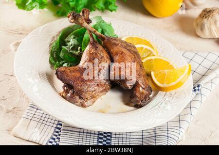 Les pattes de canard confite avec de l'orange et de la salade sur une assiette blanche Banque D'Images